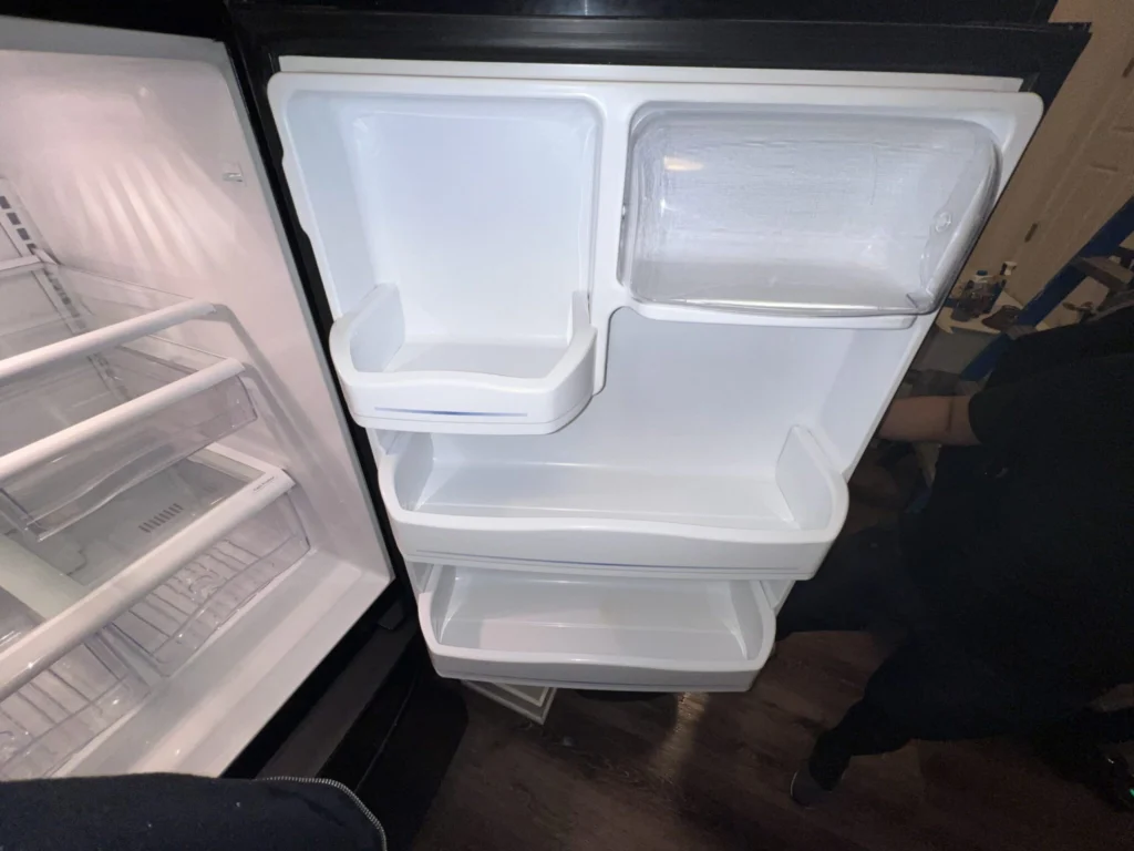 Open refrigerator with clean, empty shelves, clear drawers, and freshly wiped door compartments ready for use.