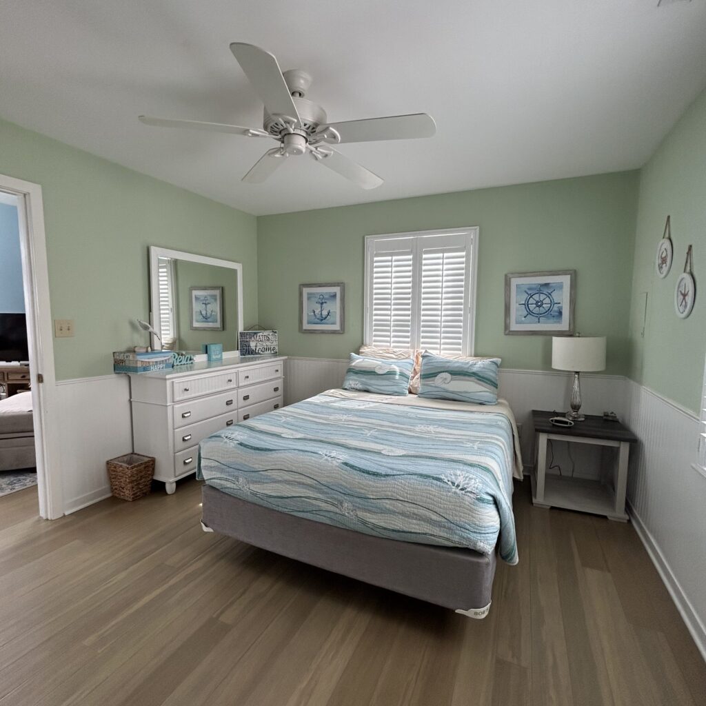 Coastal bedroom with sage green walls, nautical decor, and beach-print bedding.