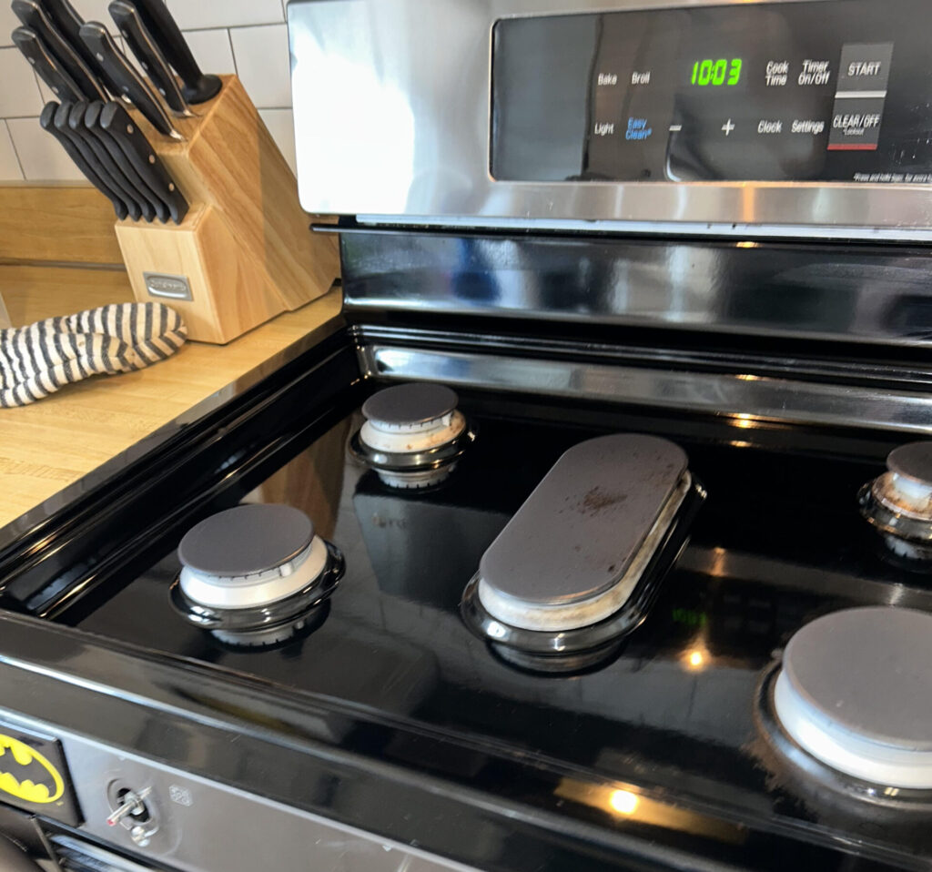 Black electric stovetop with four burners beside a wooden knife block.