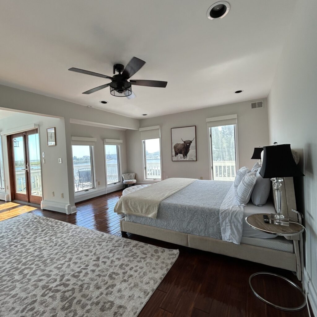 Waterfront bedroom with bay views, upholstered bed, and balcony access.